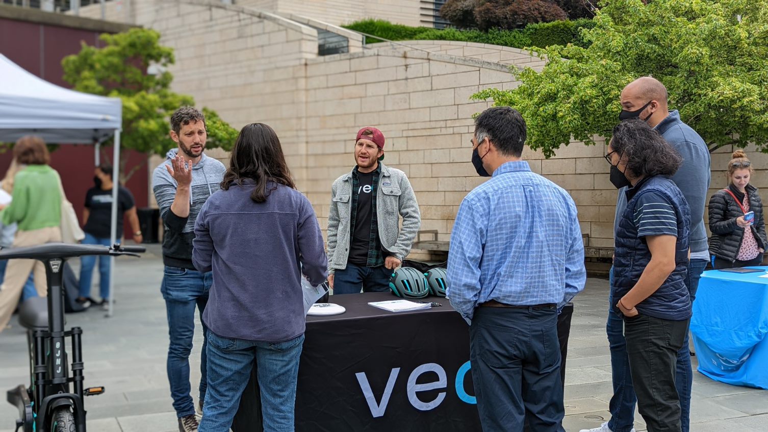 People interacting with Veo scooter share staff at their booth at a Seattle community event