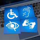 Four cards with disability-related icons sit on top of a Mac laptop keyboard