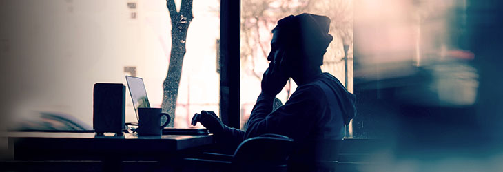 A woman talks on a phone in front of a computer