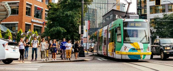 a streetcar and pedestrians waiting to cross at an intersection