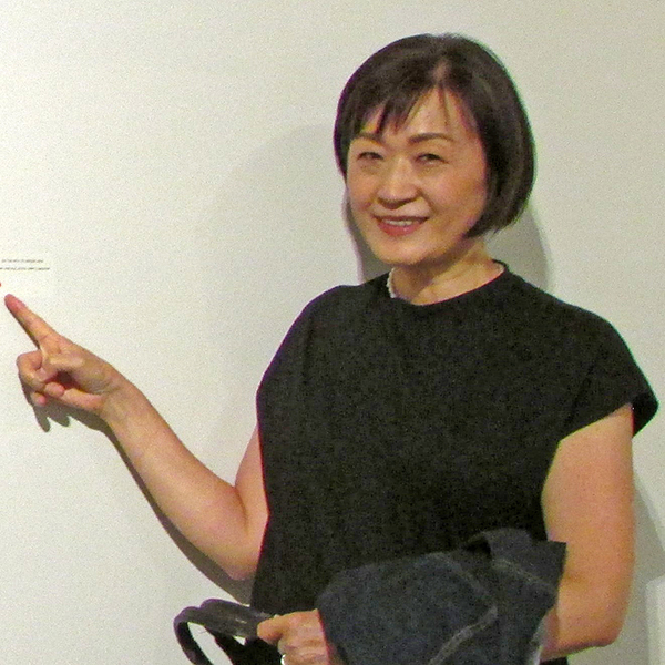 Naoko Morisawa pointing to her name on an artwork label.
