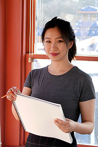 Vivian Li holds a sketchpad and pencil inside the Fremont Bridge tower