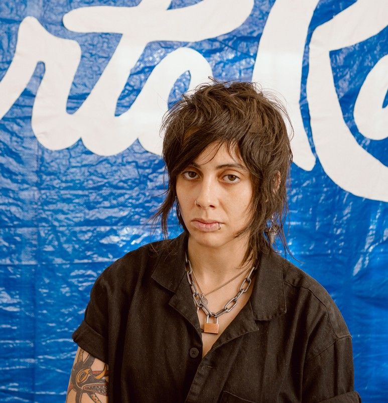 Jo Cosme has short swoopy black hair and wears chunky metal jewelry and a black shirt