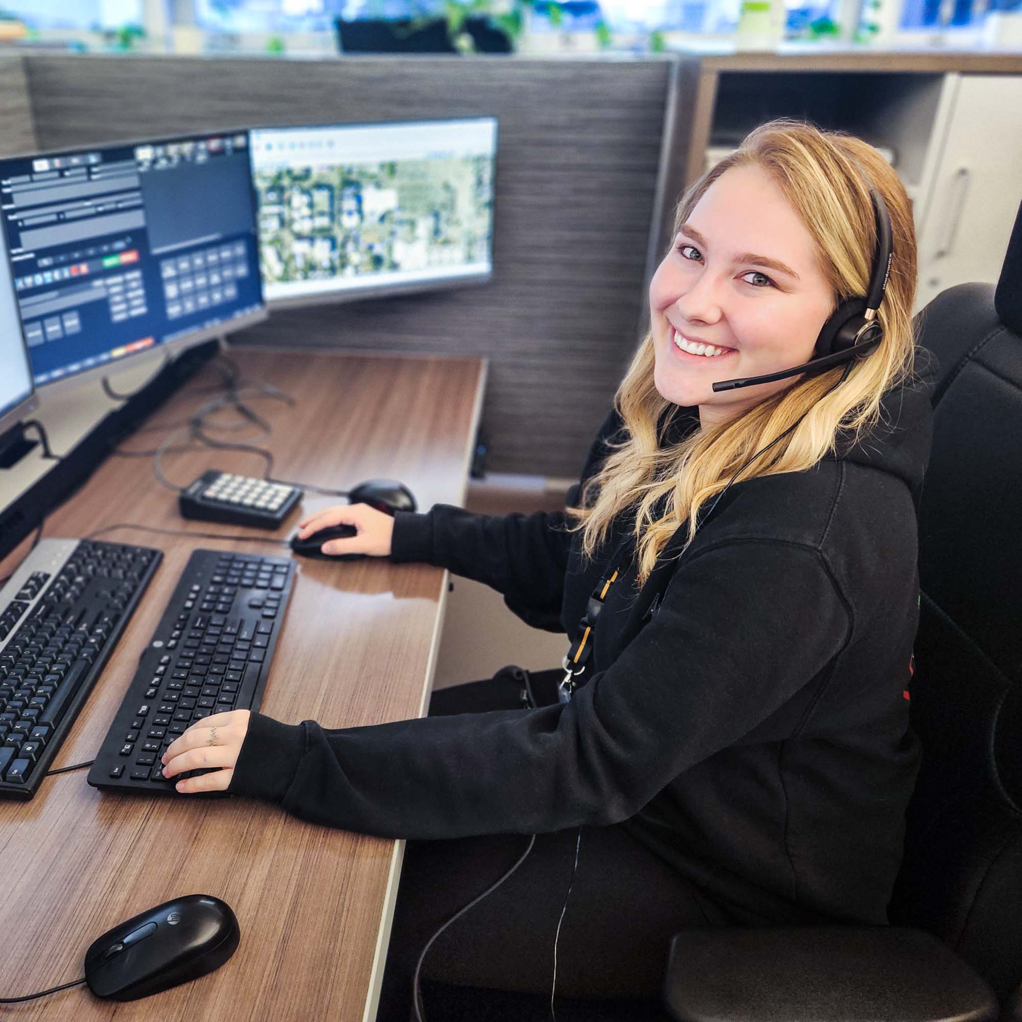 911 dispatcher seated at desk with computer monitors.