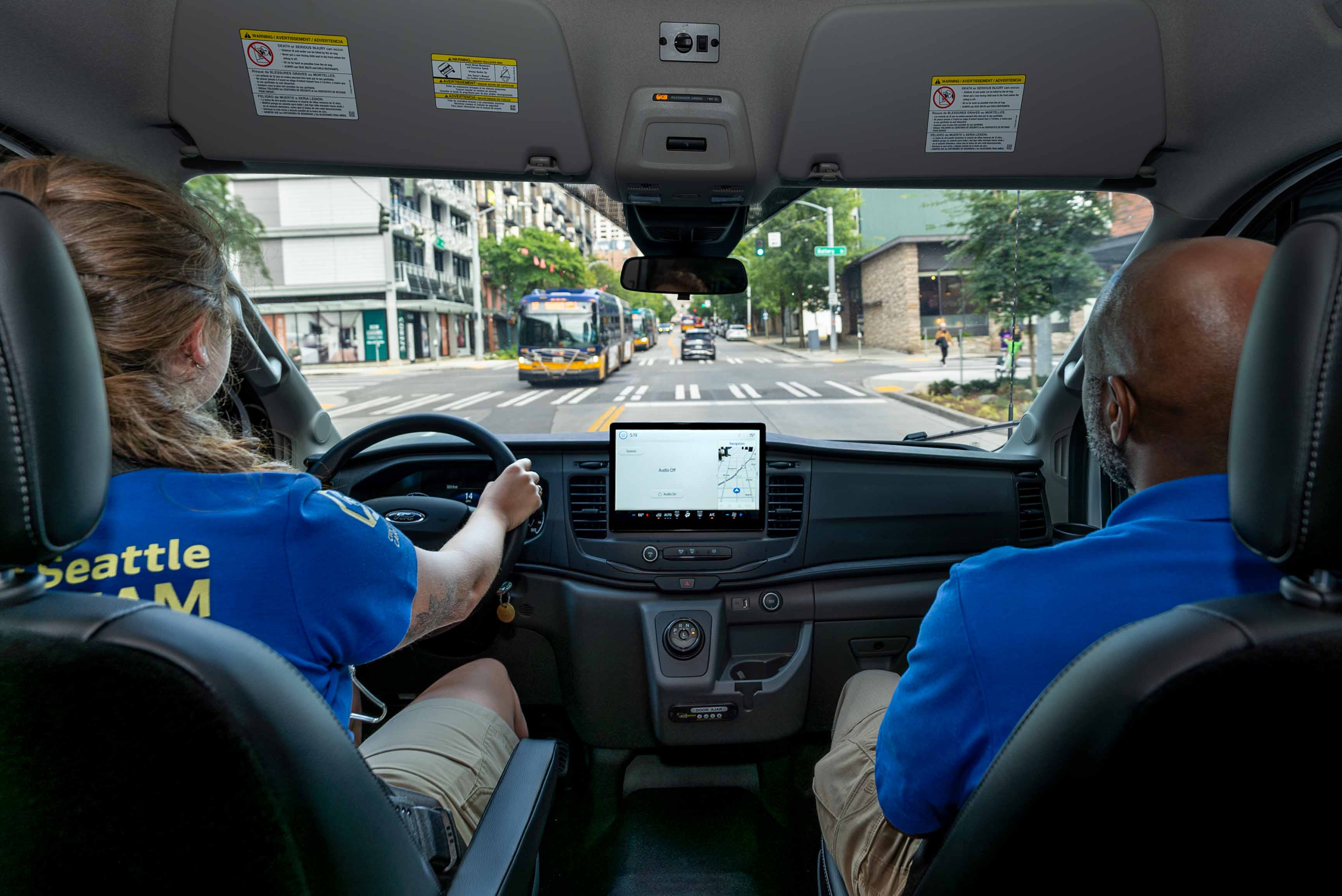 Two CARE community crisis responder employees driving south on Third Avenue in Seattle in a community crisis responder vehicle.