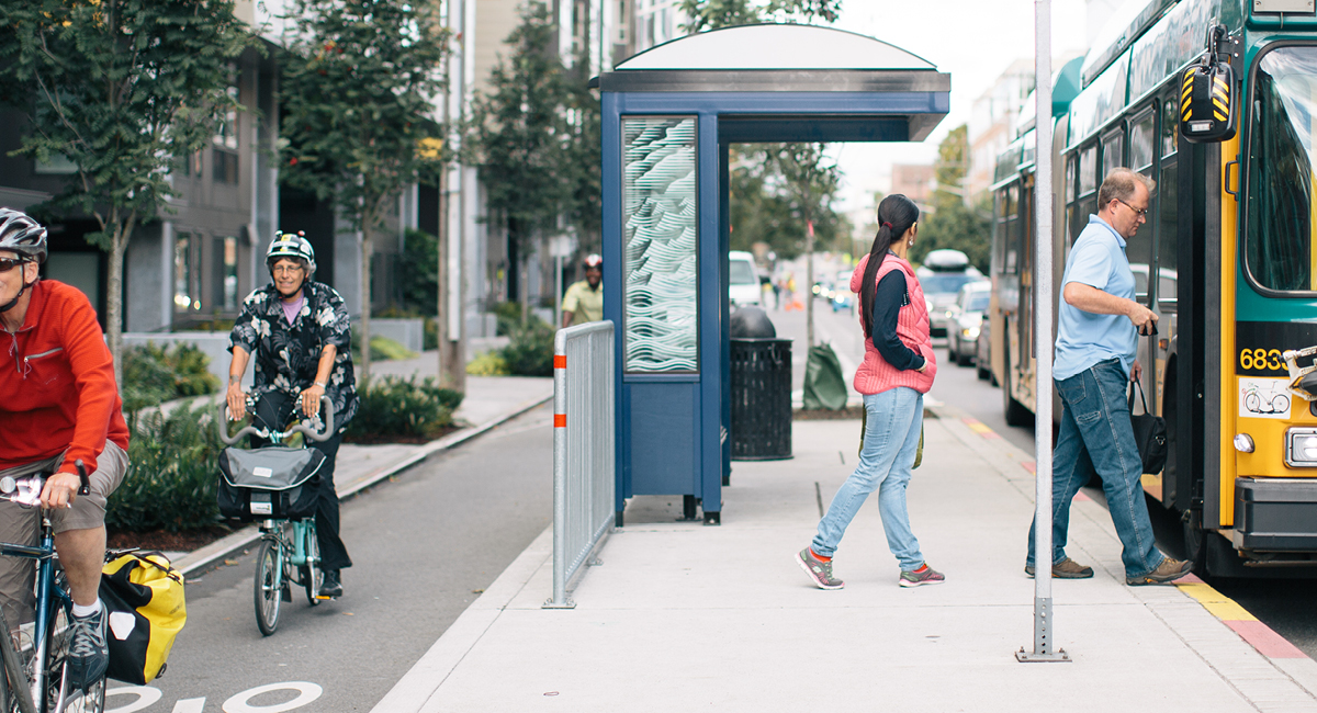 People boarding Metro bus next to bikers using separated bike lane