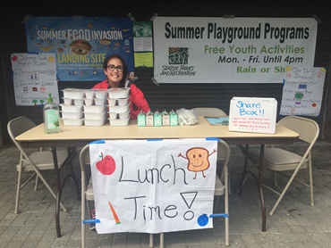A staff sits at the table for the Summer Lunch Program