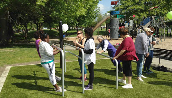 A young girl uses outdoor exercise equipment to exercise in a park