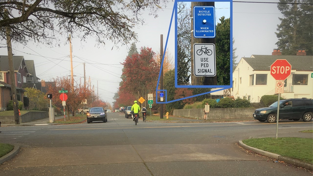 Bicycle detection sign at a neighborhood greenway arterial crossing. A light turns on to let cyclists know that the signal has detected them and will soon give them priority to cross.