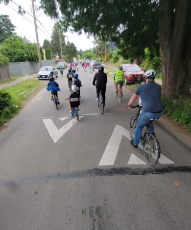A group of bikers ride on a street with a speed hump