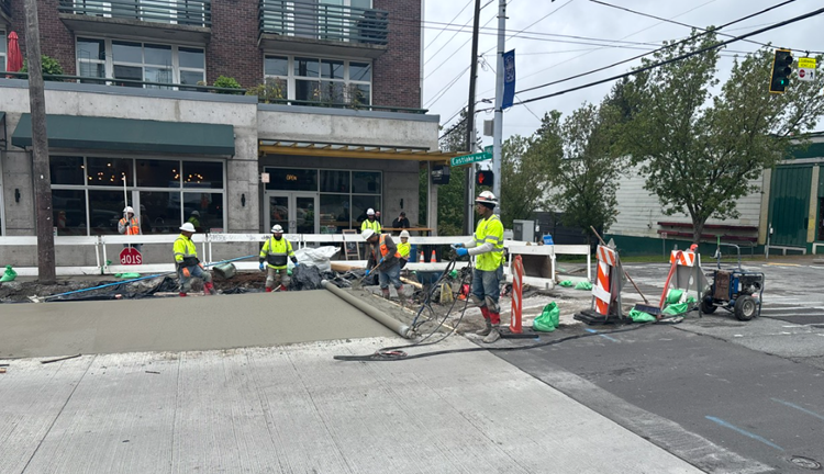 Image shows the construction team placing new concrete on the west side of Eastlake Ave E just south of E Lynn St