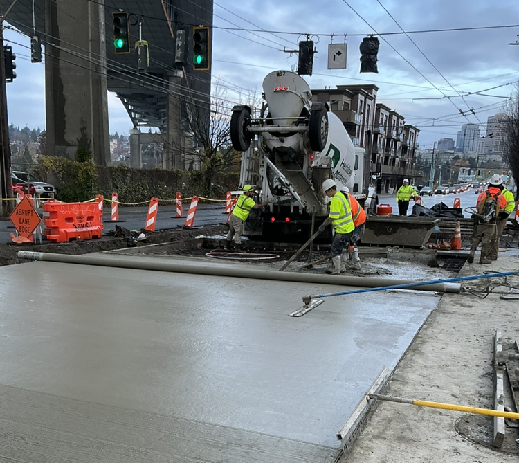 Image shows the pouring of concrete to form the new street surface on Eastlake Ave E
