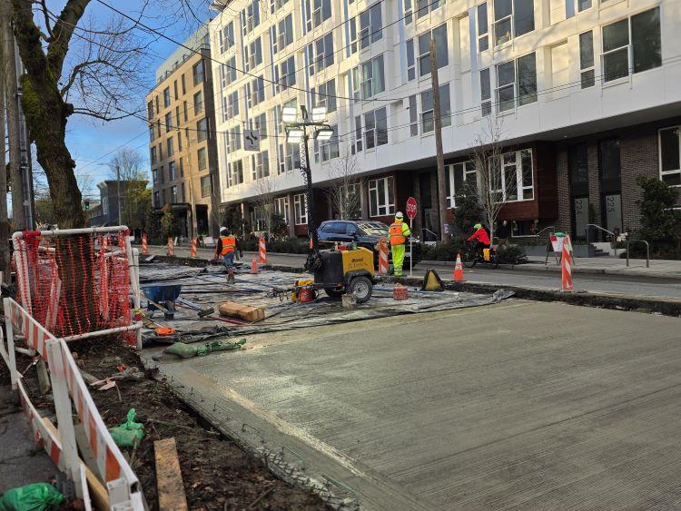 Image shows crews controlling traffic next to fresh concrete on Eastlake Ave E.