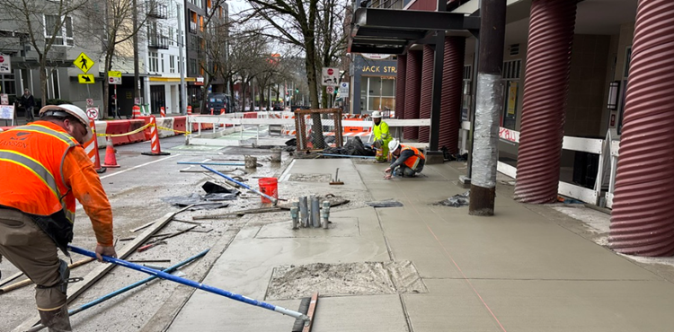 Image shows our team pouring new concrete sidewalk along Roosevelt Way NE