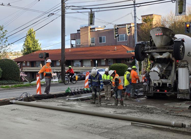 Image shows crews pouring concrete at the intersection of Eastlake and Roanoke.