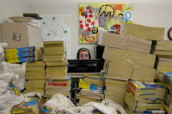 Person sitting at a desk surrounded by phone books
