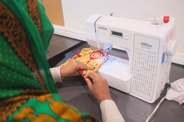 Woman sewing a piece of fabric on a sewing machine during a textile mending and upcycling class.