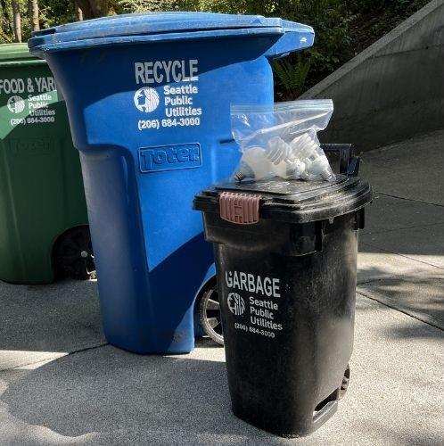 A bag of CFL bulbs on bin.