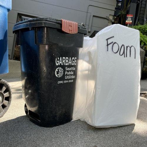 A bag of foam blocks near a garbage bin.