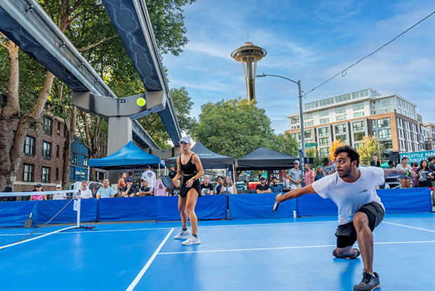 Two people playing pickleball under the Space Needle.