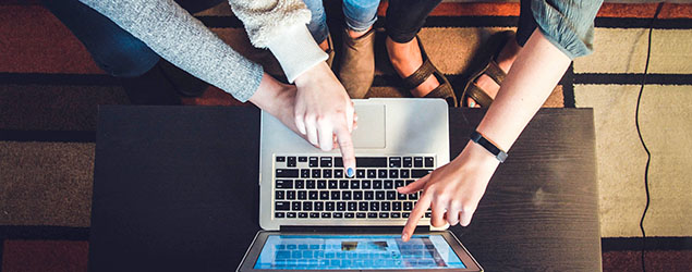 People point at the screen of a laptop