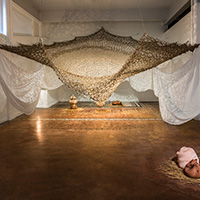 Hanako O’Leary's large-scale fiber installation, "Yomi," which features brown and white fibers hanging from the walls and ceiling.