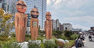 Three large wooden sculptures stand on the Waterfront.