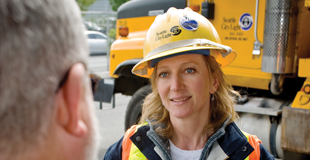 Woman in hard hat speaking to man in foreground