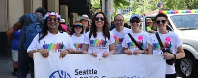 Group of people holding up LGBTQ Commission banner