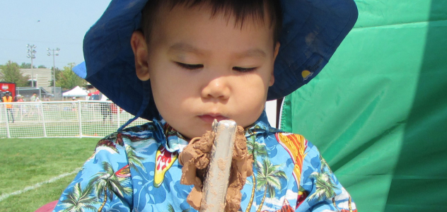 Child outside holding a stick with clay on it