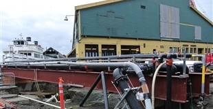 Road construction taking place on the downtown waterfront in front of the Seattle aquarium and a tour boat