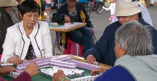 An elderly woman in a wheelchair talks with friends