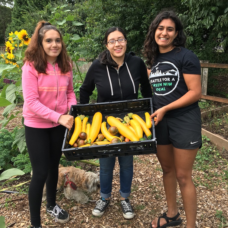 Youth holding large tray of just harvested squash and tomatoes