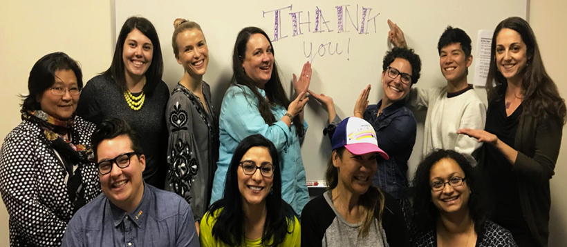 Staff at partner agency posing in front of Thank You message written on a whiteboard