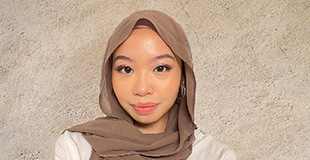 Portrait of Sabreen, a young Cham woman wearing a loose headscarf and smiling slightly.