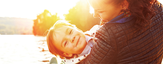 a mother holding her child with the sun setting in the distance