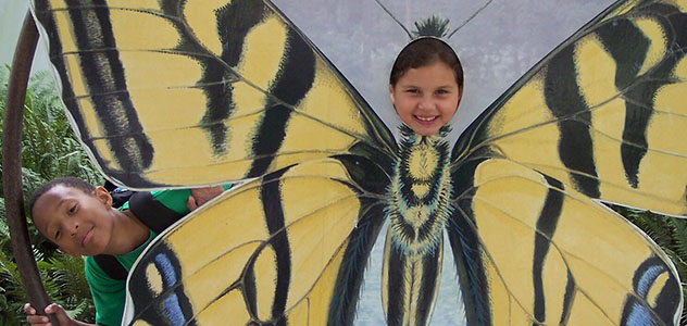 Children pose with a butterfly painting