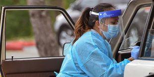 A nurse administering a COVID test at a drive-through testing site