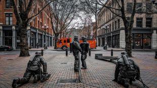 Statues of firefighters in Seattle's Pioneer Square with a fire engine parked in the background