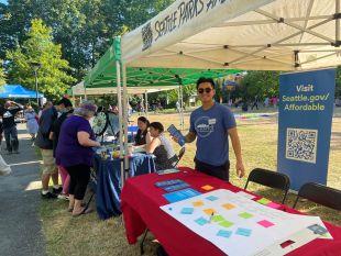 A City staffer smiling an at "Affordable Seattle" program booth at an outdoor event