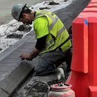 Crew member installing a concrete curb on the 4th ave PBL