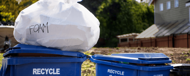 Bagged foam blocks on top of recycling bin.