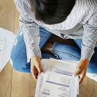 Person sitting on floor holding utility bills