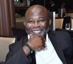 Headshot of a smiling man in a navy blue blazer and white shirt
