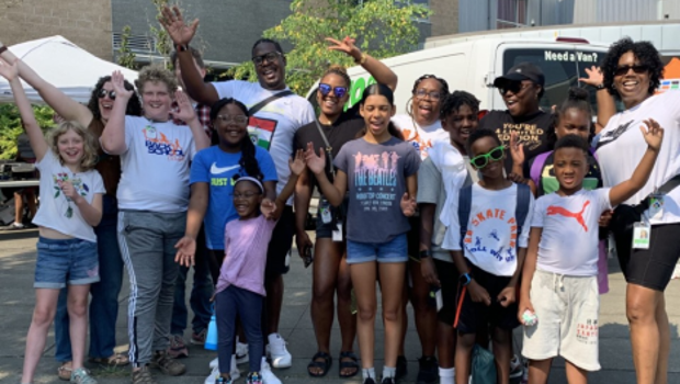 A group of kids at a community event raising their arms