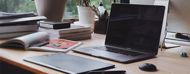 A laptop and its accessories sit on a desk next to books