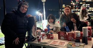 A group of teens poses at an outdoor activity table at night