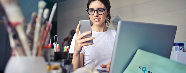 A woman with a laptop checks her phone