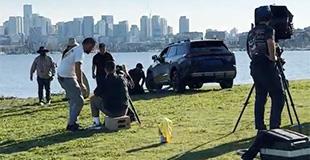 A film crew getting footage of a toyota parked with the Seattle skyline in the background
