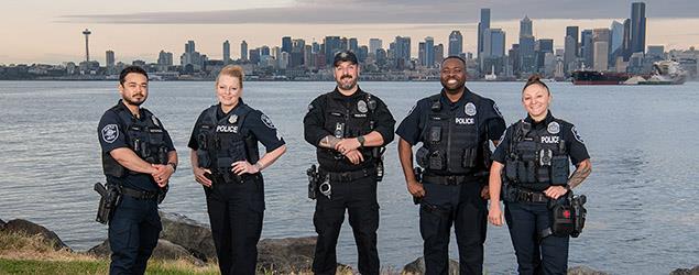 Officers stand in front of Elliot Bay with downtown Seattle in the background